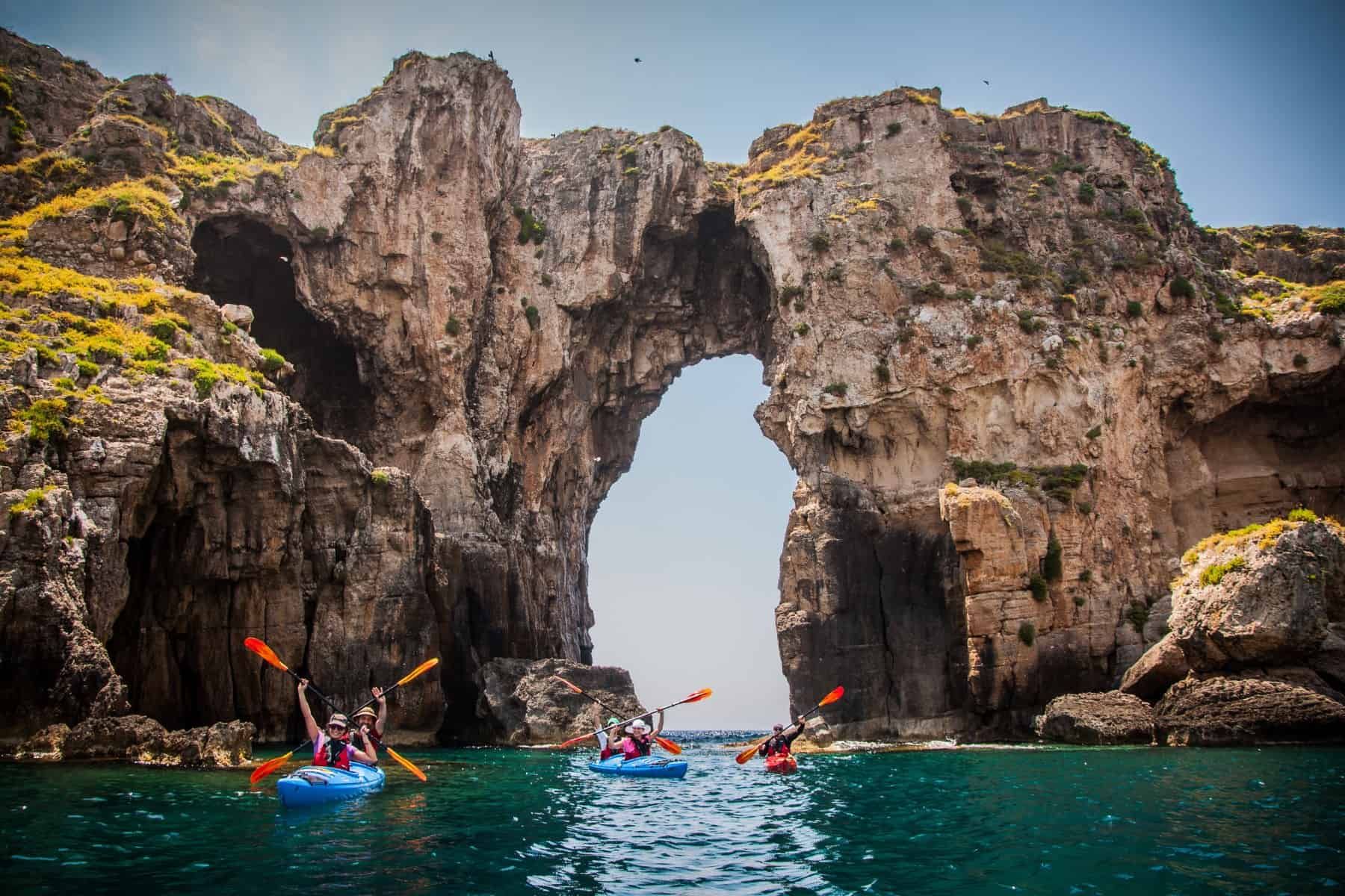 Kayakers under the sea arch at the mouth of the Bay of Navarino